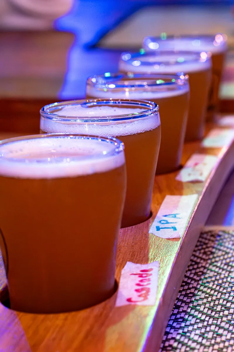 A flight of pale craft beers with hand-labelled tags — Cascade and IPA